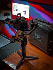 A professional camera and gimbal setup featuring a DJI Ronin SC on a wooden desk.